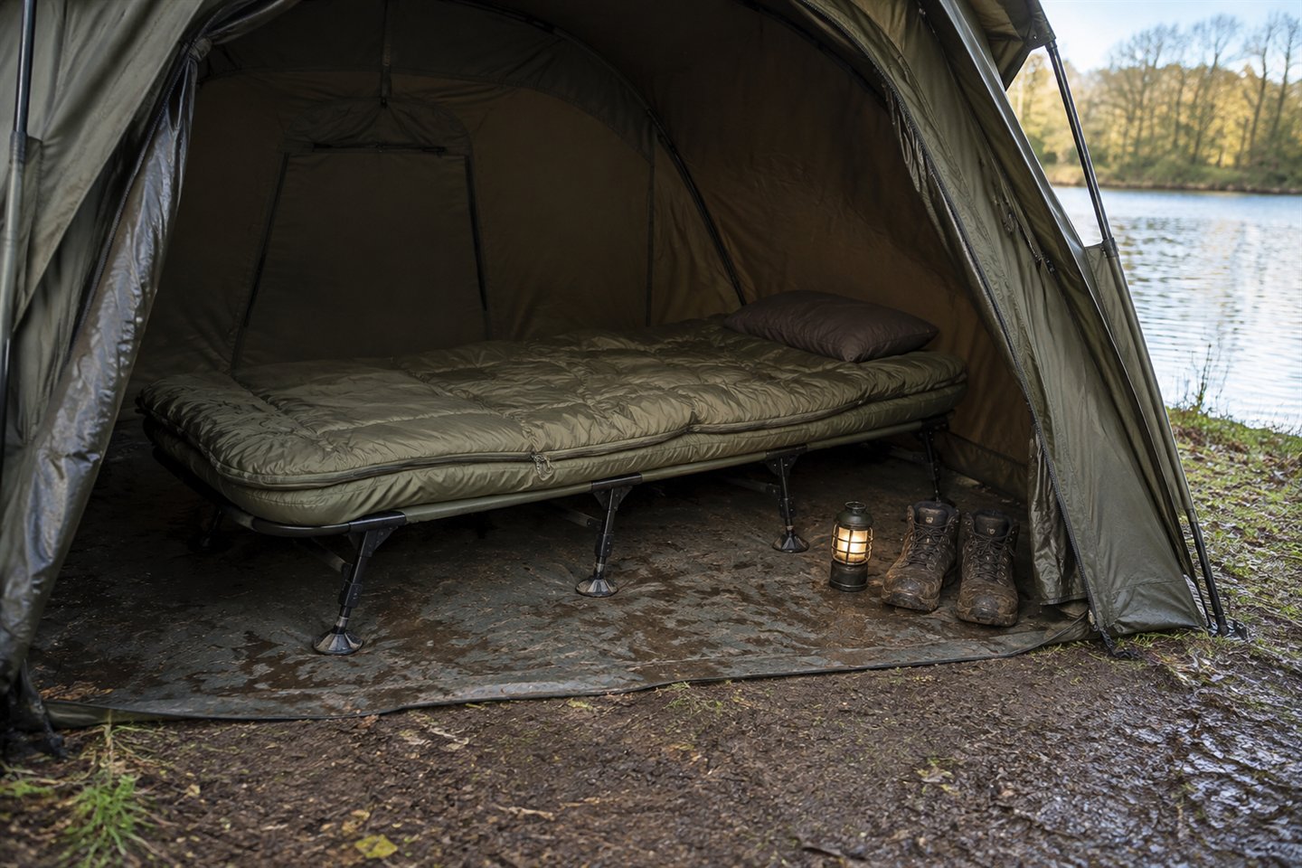 A level carp bedchair and attached sleeping bag arranged inside an open-fronted bivvy