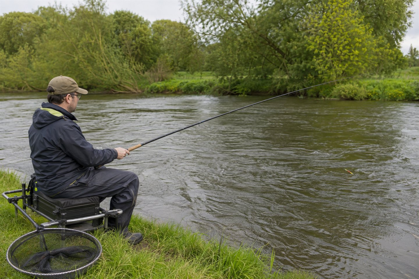 River angler guiding a red-tipped stick float through a steady coarse-fishing glide